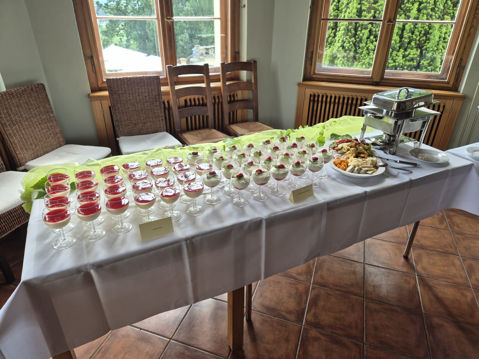 Buffet mit lächelnden Desserts in Rot und Weiß, grünes Tuch, Fensterlicht