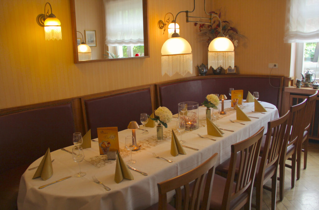 Festlich gedeckter langer Tisch mit weißen Blumen und warmen Lampenlicht