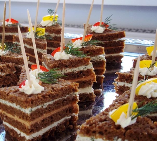 Schichtkuchenwürfel in Braun und Weiß mit Sahnetupfen und Kräutern