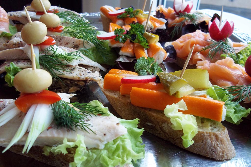 Bunte belegte Brote mit Lachs Oliven Kraeutern und Gemuese auf Platte
