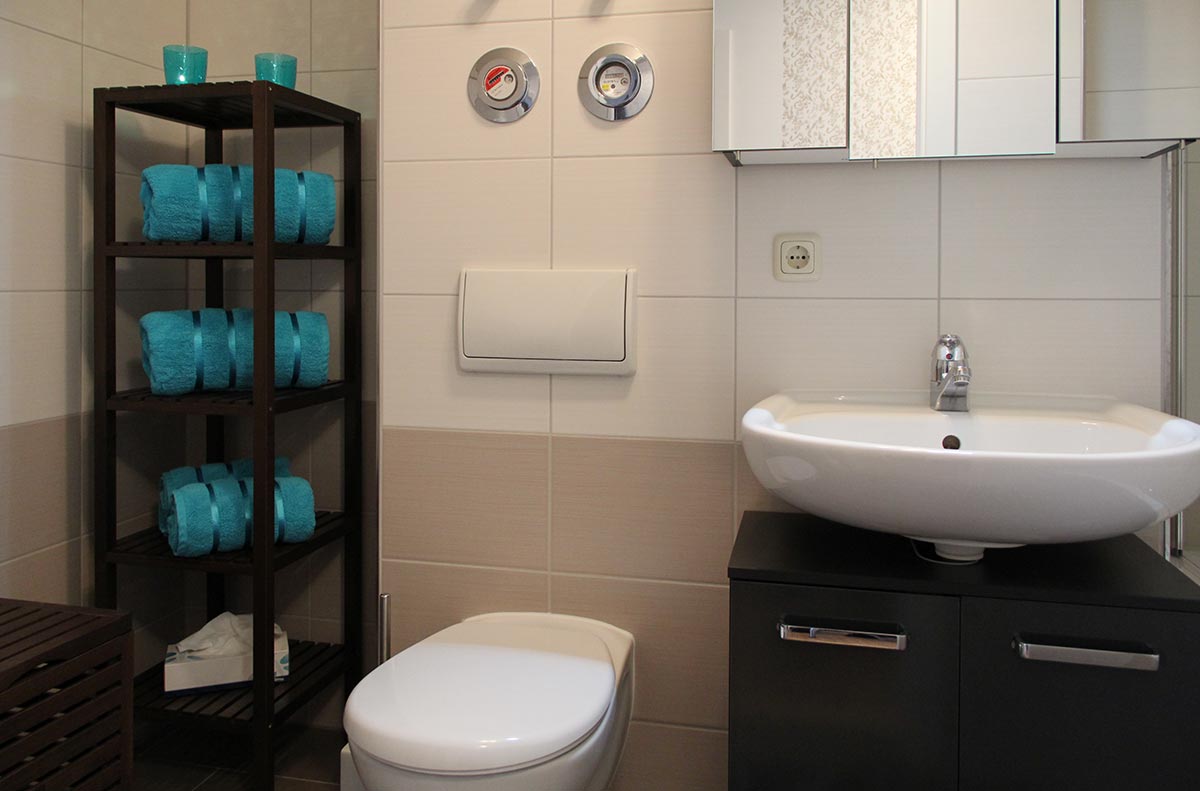 Modernes  Bad  in  Beige  und  Schwarz  mit  Waschbecken  und  türkisfarbenen  Handtüchern