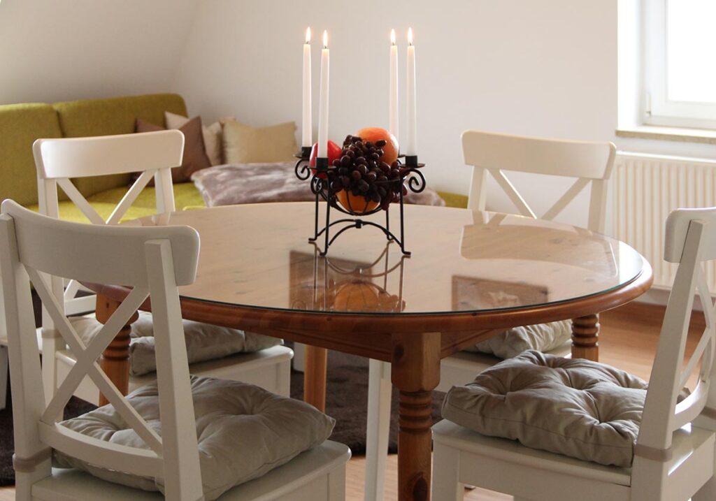 Runder Holztisch mit Kerzenleuchter und Stuehlen in hellem Zimmer