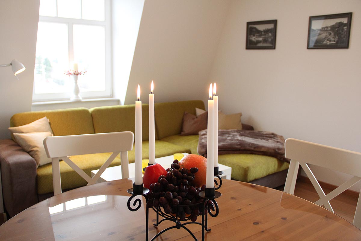 Gemütliches  Wohnzimmer  mit  grünen  Sofas  Kerzen  und  Obstschale  auf  Holztisch
