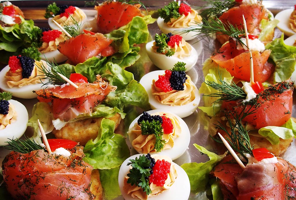 Bunte Vorspeisenplatte mit Lachsröllchen auf Salat und gefüllten Eiern, frisch