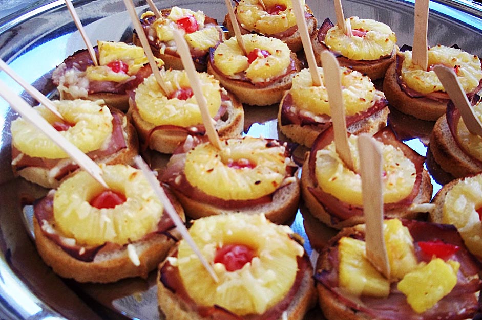 Fingerfood mit Ananasringe und Schinken auf Brot in Gelb und Braun auf Tablett